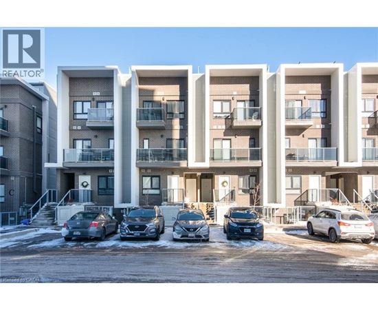 A row of modern apartment buildings with cars parked in front.
