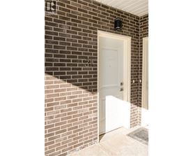 A white door is on the left side of a brick wall.