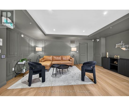 A living room with a brown leather couch and black chairs.
