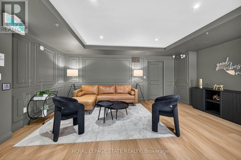 A living room with a brown leather couch and black chairs.