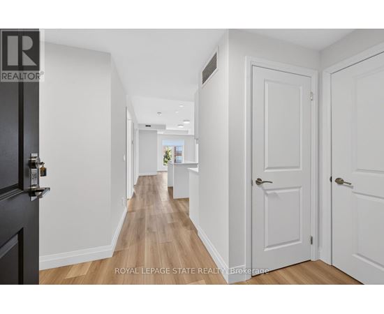 A hallway with white doors and a black door on the left.