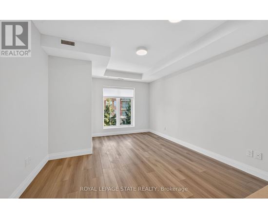 A spacious room with wooden flooring and white walls.