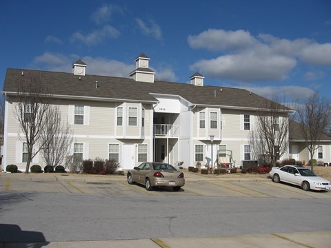 A white building with a parking lot in front.