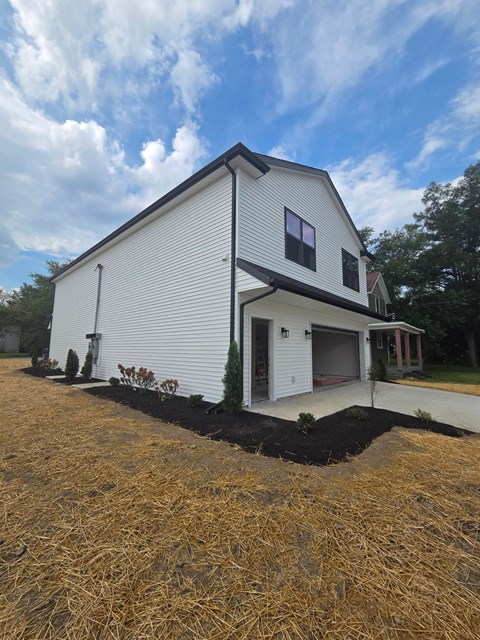 A white house with a black roof and a garage door.