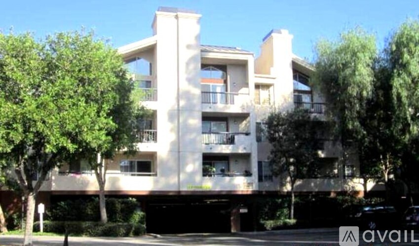 A modern building with balconies and trees in front.