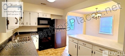 A kitchen with white cabinets and a black fridge.