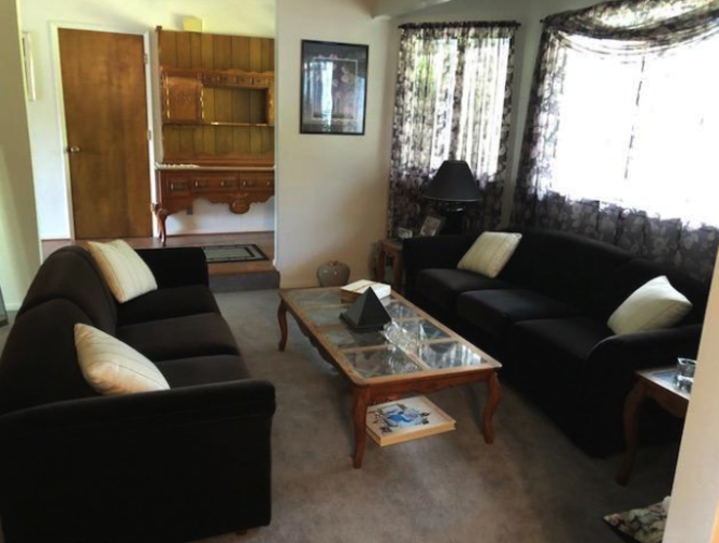 A living room with black couches and a wooden coffee table.