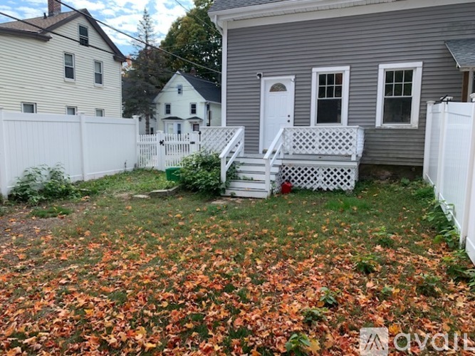 A backyard with a white fence and a house in the background.