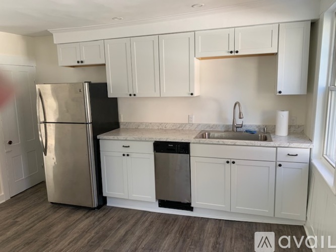 A kitchen with white cabinets and a stainless steel refrigerator.