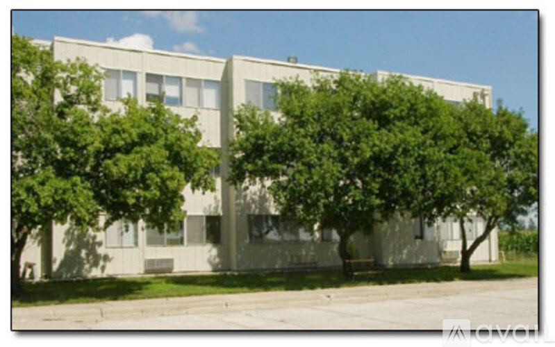 A grey building with trees in front.