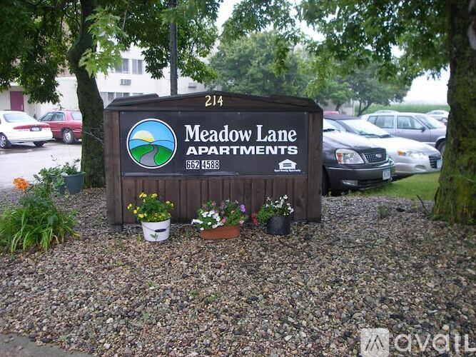 A sign for Meadow Lane Apartments is shown in front of a parking lot.