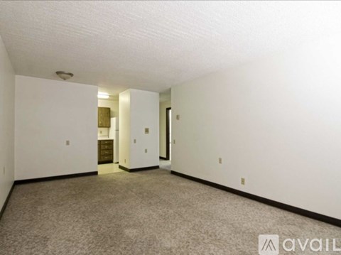 A spacious room with carpeted floor and white walls.