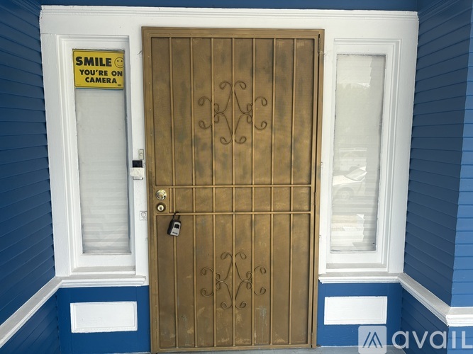 A brown door with a sign on the window that says "Smile you're on camera".