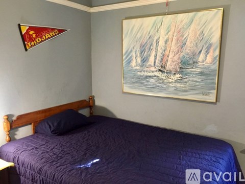 A bedroom with a bed and a painting of a sailboat on the wall.