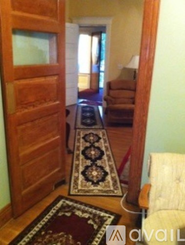 A hallway with a rug on the floor and a door on the left.
