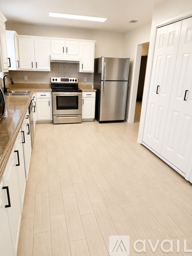 A kitchen with white cabinets and appliances.