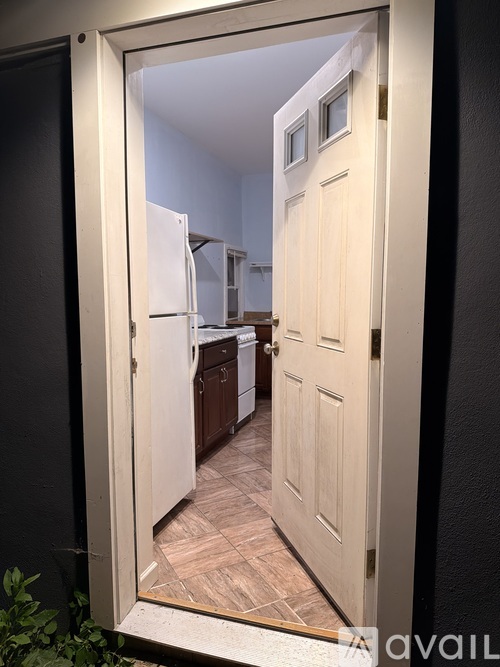 A white door is open to a kitchen.