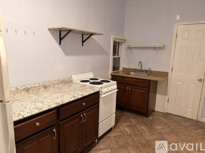 A kitchen with a white stove top oven and a sink.