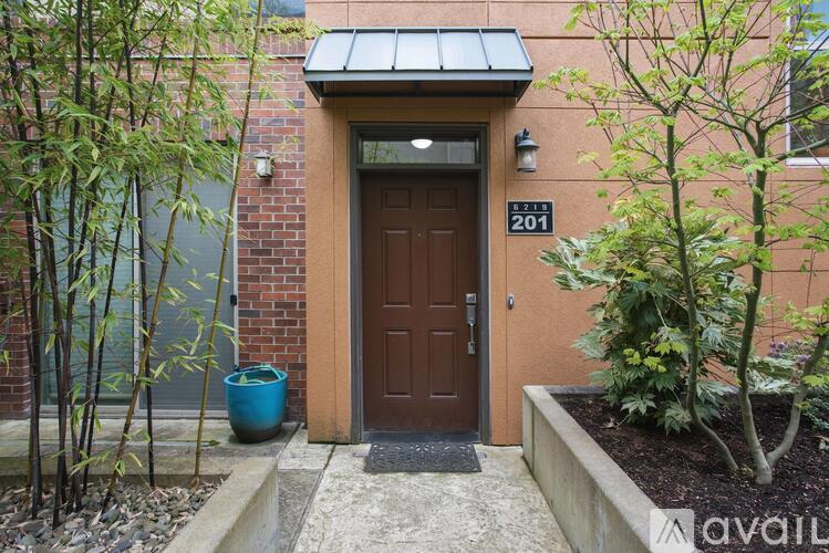 A brown door with the number 201 on it is flanked by two trees.