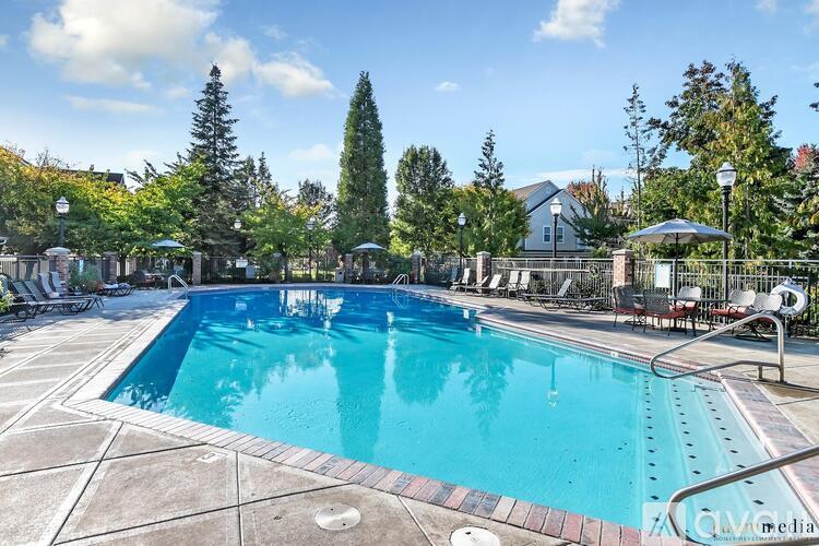 A large outdoor swimming pool surrounded by trees and lounge chairs.