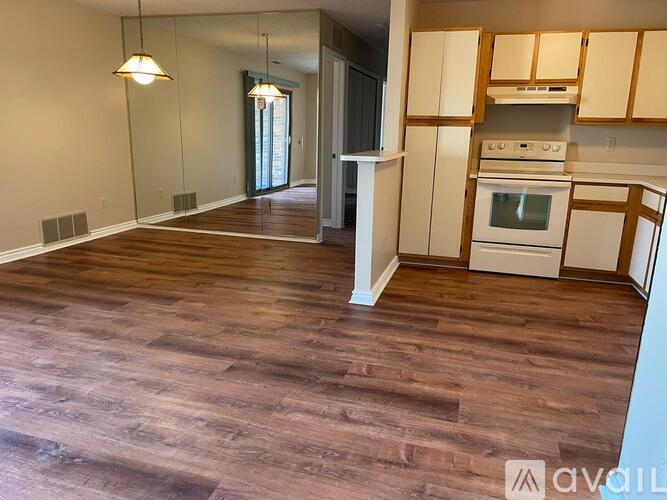 A kitchen with white cabinets and a wood floor.