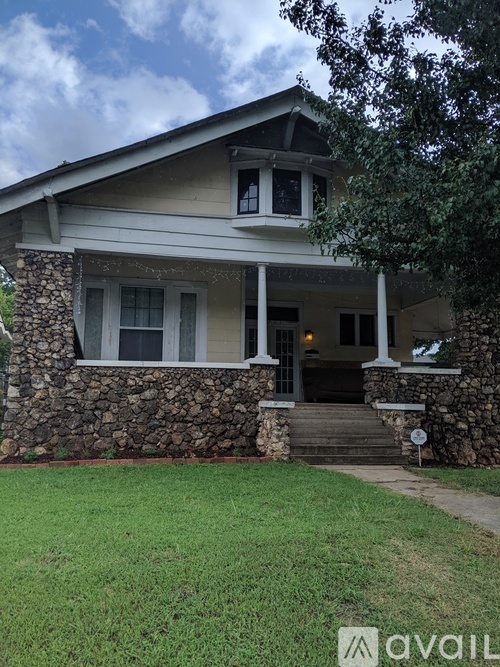 A house with a stone wall and a porch.