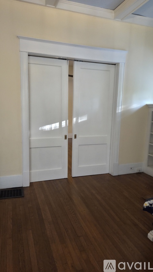 A room with a white door and wooden flooring.