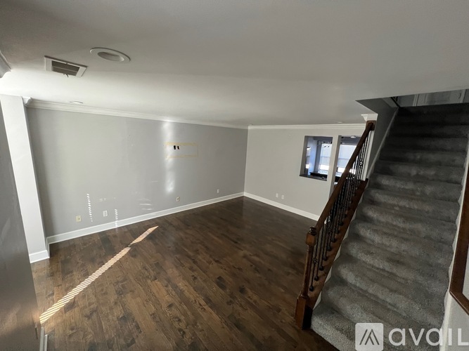 A room with wooden floors and a staircase leading to another level.