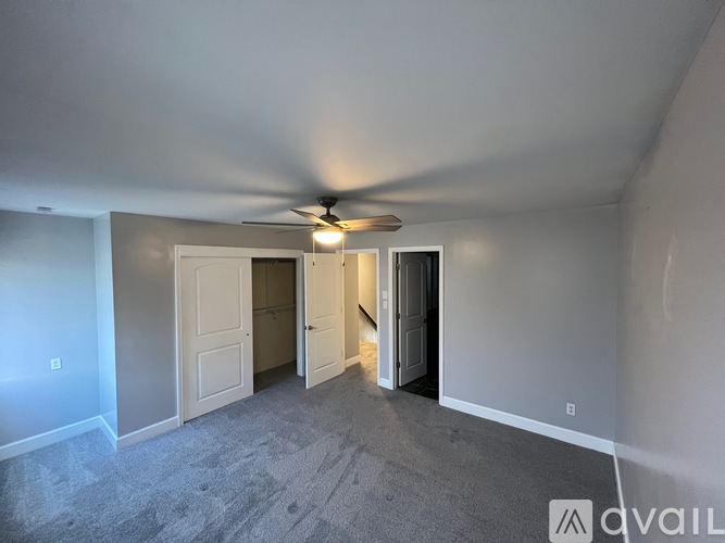 A room with a ceiling fan and carpeted floor.