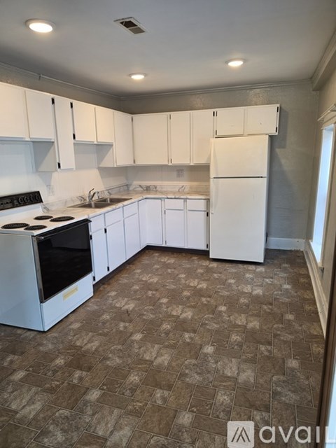 A kitchen with white cabinets and a tiled floor.