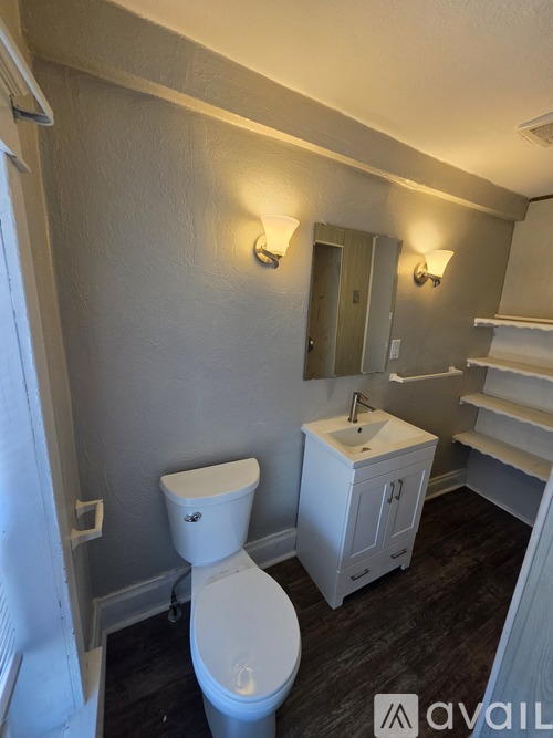 A white toilet sits in a bathroom with a white sink and a mirror.