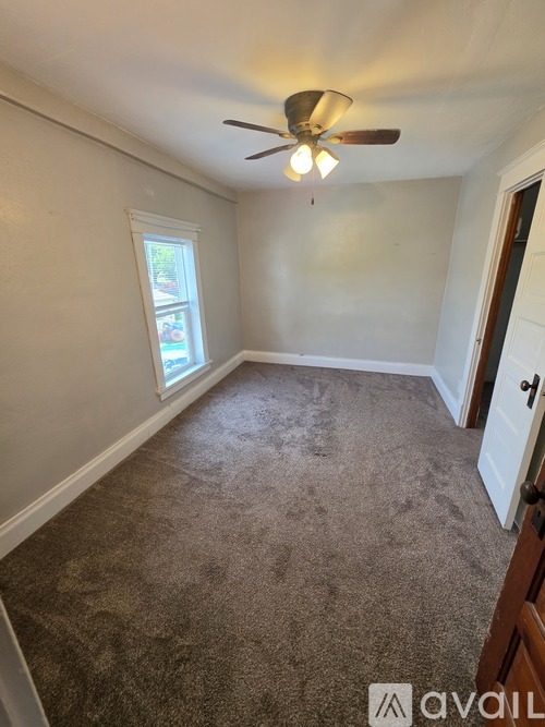 A room with a carpeted floor and a ceiling fan.