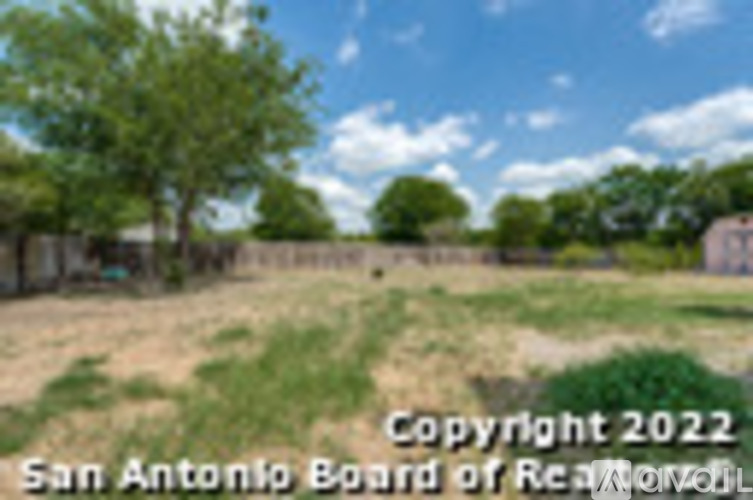 A field with a fence and trees in the background.