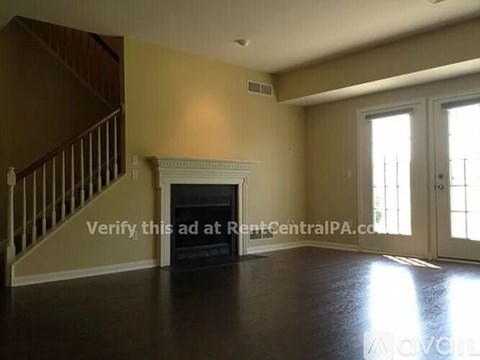 A living room with a fireplace and a staircase.