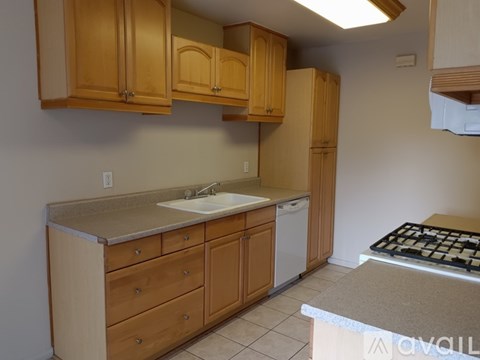 A kitchen with wooden cabinets and a white dishwasher.