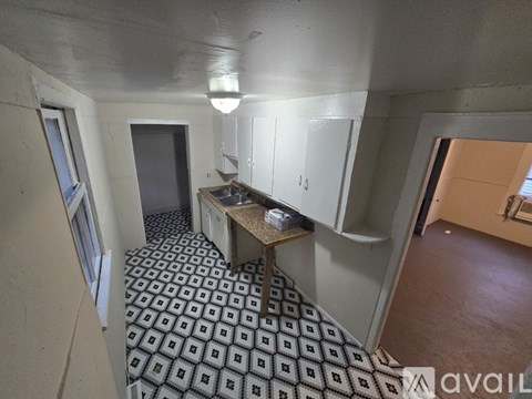 A kitchen area with a sink and a patterned floor.