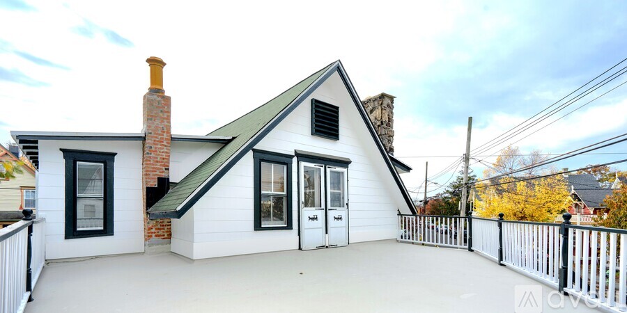 A small white house with a black roof and a chimney.