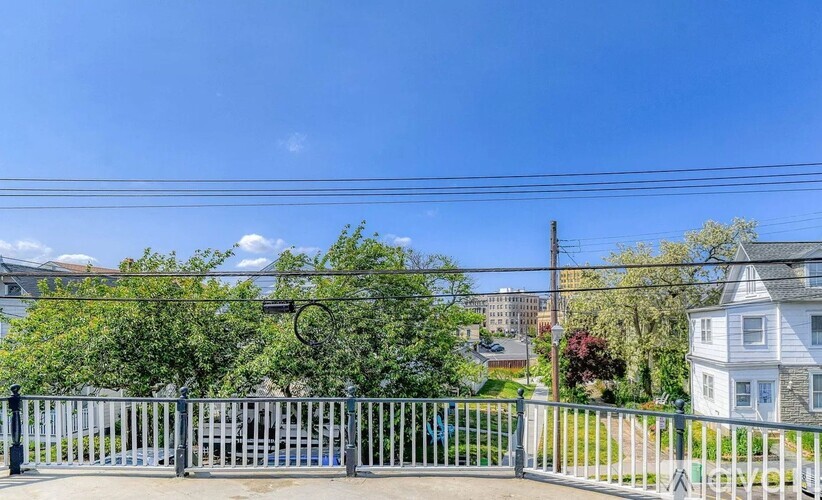 A fence with a gate in front of a house and trees.