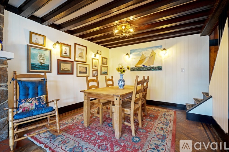 A wooden table and chairs are set up in a room with a stone fireplace and pictures on the wall.