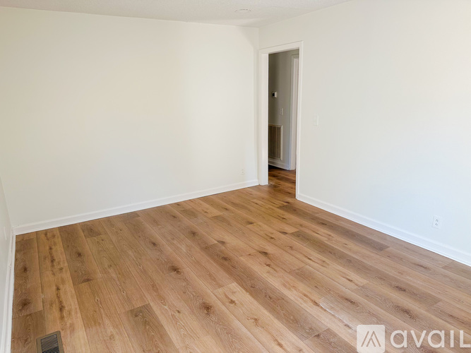 A room with wooden flooring and a doorway leading to another room.