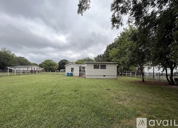 A grassy field with a fence and a couple of buildings in the distance.