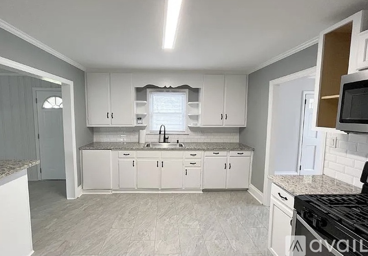 A kitchen with white cabinets and a black stove top oven.