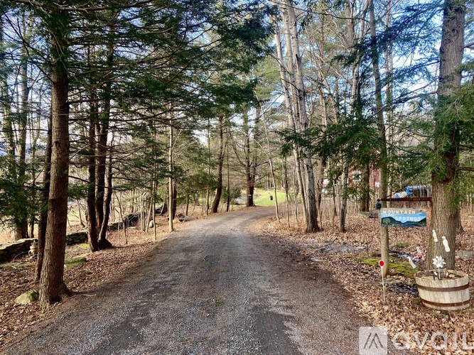 A dirt road surrounded by trees with a sign on the right.