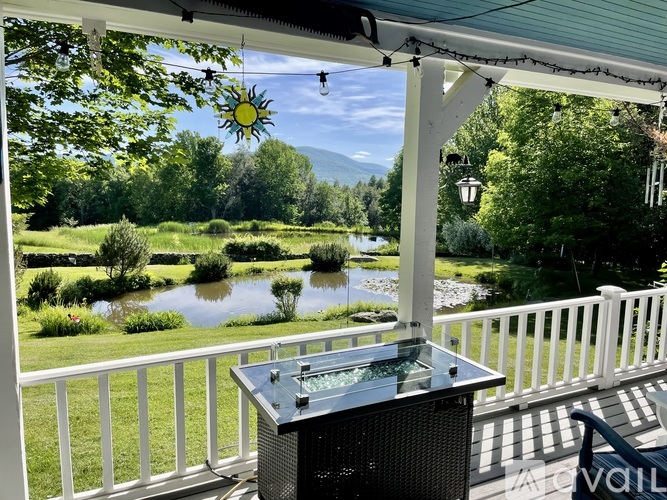 A hot tub sits on a deck overlooking a pond and trees.