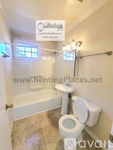 A bathroom with a toilet, tub, and window.