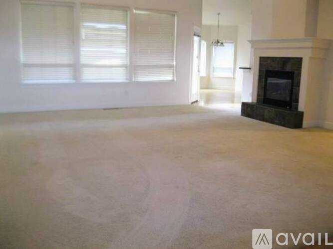 A large, empty room with a fireplace and a chandelier.