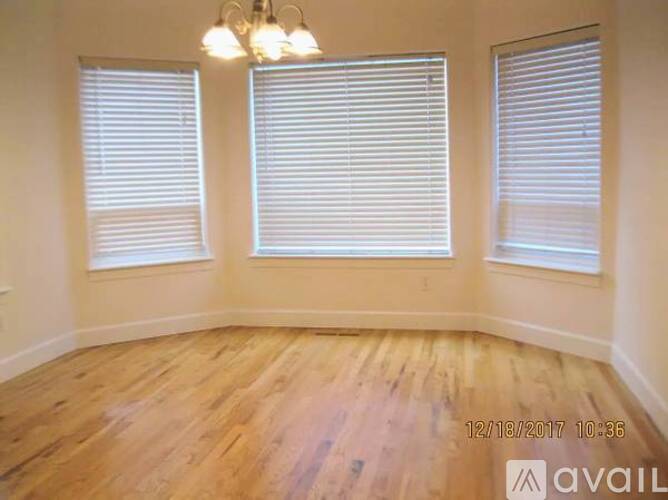 A room with wooden floors and two windows with blinds.