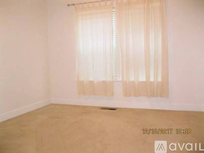A room with a window covered by a sheer curtain.
