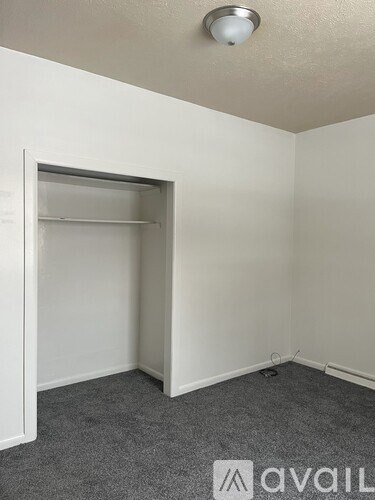 A small, empty room with a grey carpet and a white door.