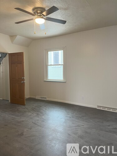 A room with a ceiling fan and a door.